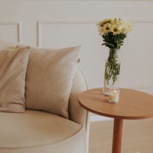 A peaceful interior with a minimalist aesthetic featuring a beige sofa, wooden table, and flowers.