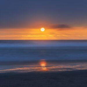 A tranquil sunset viewed over Chilca Beach, Peru, with vibrant ocean colors.